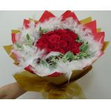 鲜花:22枝黄玫瑰点缀绿叶，粉色卷边纸圆形包装，绿色和红色丝带束扎。